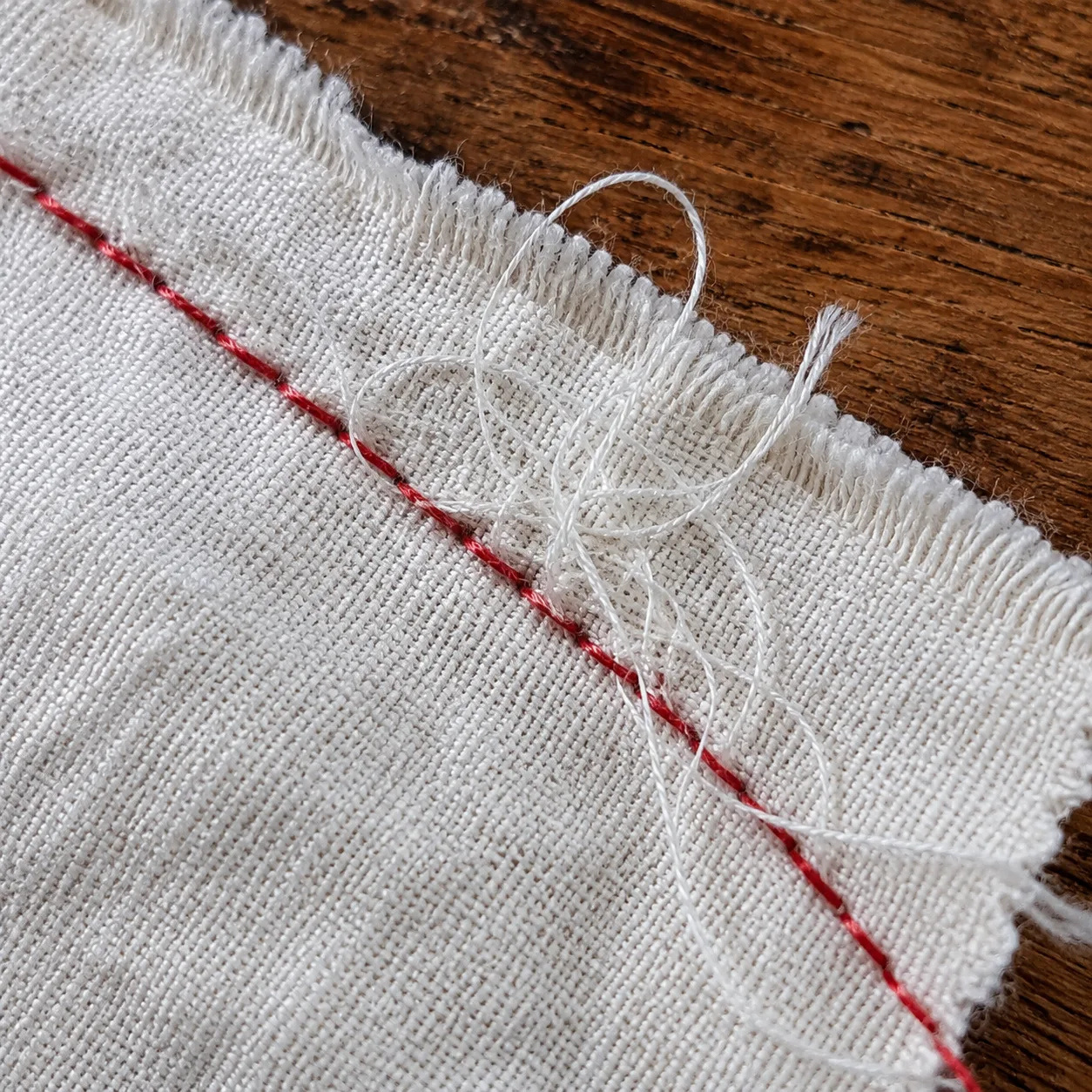 Le fil emmêlé sous le tissu est blanc, alors que la canette est rouge